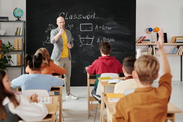 Teacher in classroom, teaching students.